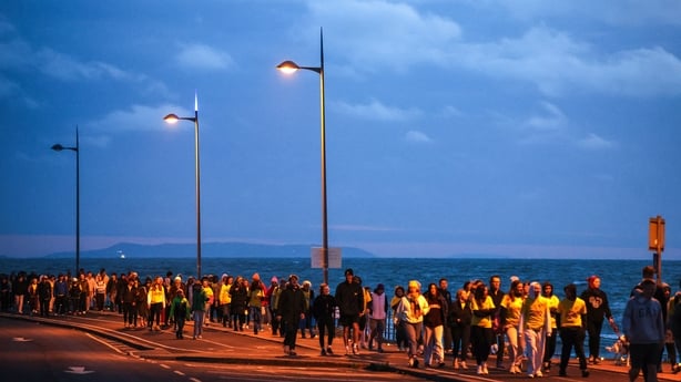 People walk along the coast during Darkness Into Light Greystones