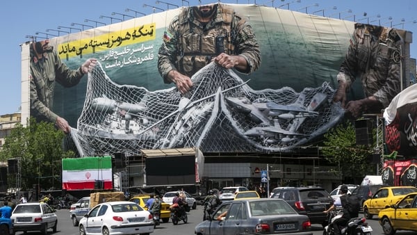 A poster in Tehran depicts Iranian soldiers holding a net in the shape of the Strait of Hormuz, with US military aircraft ensnared in it.