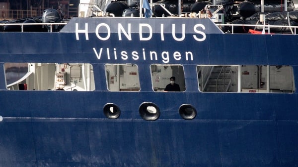 A person wearing a mask is seen on the deck of the MV Hondius after docking in the Granadilla Port