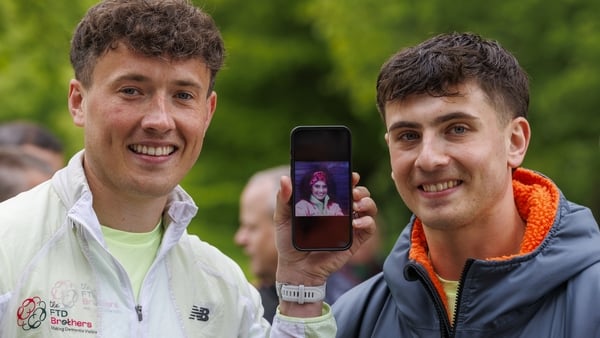 Jordan Adams holds an image of his mother Geraldine as he stands with his brother Cian