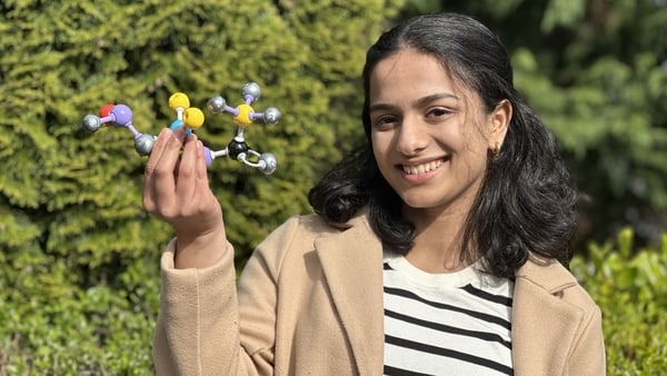 A young woman holds a model of her award-winning environmental project