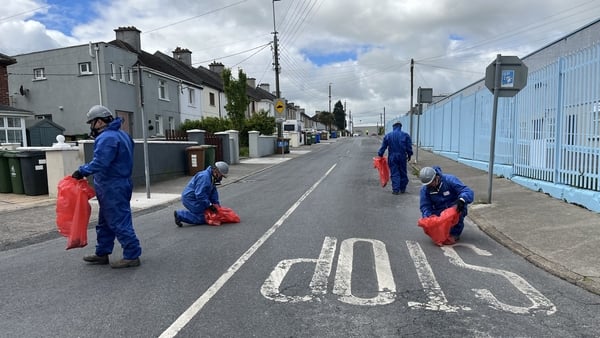 A team in protective clothing are combing the road next to the business centre in Waterford and removing debris