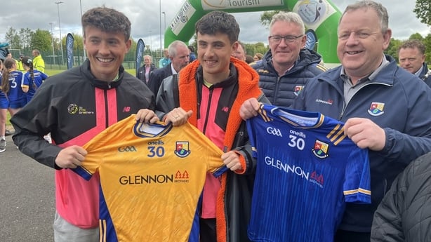 Four people smile for a photograph holding GAA jerseys