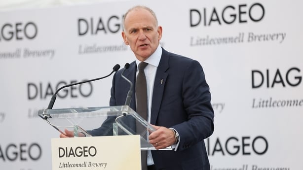 Business man speaking on a stage with Diageo branding behind him