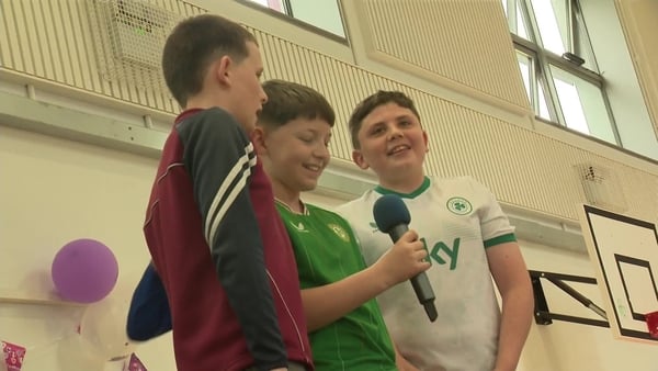 Three boys sing at a school show in their assembly hall.