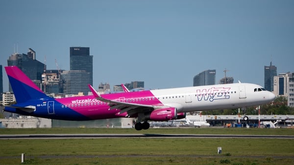 A plane with the purple,pink and white livery of Wizz Air lands at an airport