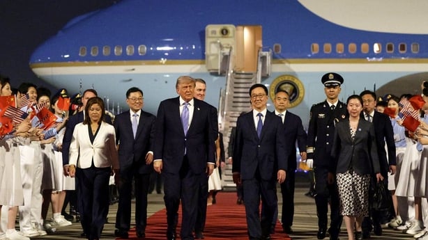 Donald Trump (C) is joined by officials as he arrives in Beijing