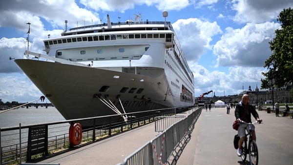 A man rides his bicycle past the Bahamas-registered cruise ship Ambition