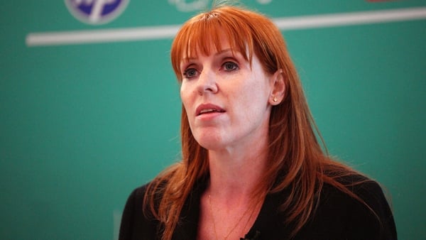 Head and shoulders image of a woman with shoulder length red hair against a green backdrop.