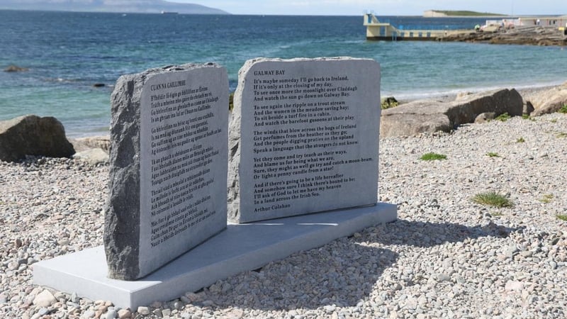 Image shows the lyrics to Galway Bay inscribed on a grey stone plaque sitting on a pebble beach.
