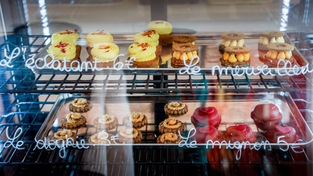 Image shows several pastry treats behind the counter of a shop.