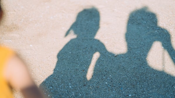 Image shows the shadow of a young girl and a man.