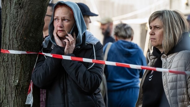 A woman talks on the phone as she observes a response effort to a missile and drone strike in Kyiv, Ukraine, on May 14, 2026