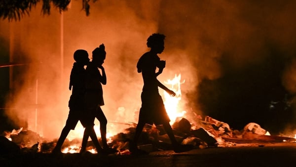 People walk past a fire set by demonstrators during a protest against the lack of energy and blackouts in Havana