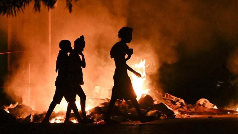 People walk past a fire set by demonstrators during a protest against the lack of energy and blackouts in Havana