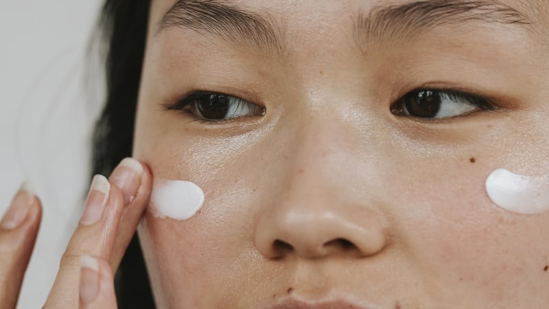 Close-up shot of young woman applying face cream
