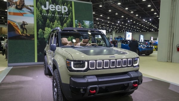 A green Jeep vehicle on display at a car show