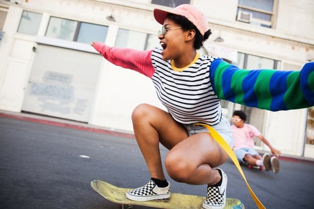 woman wearing a colorful outfit riding a skateboard down a city street