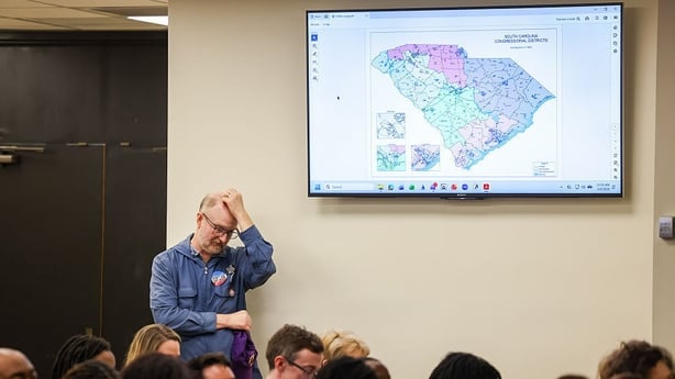 A man standing in front of a map on a wall, with his hand on his head