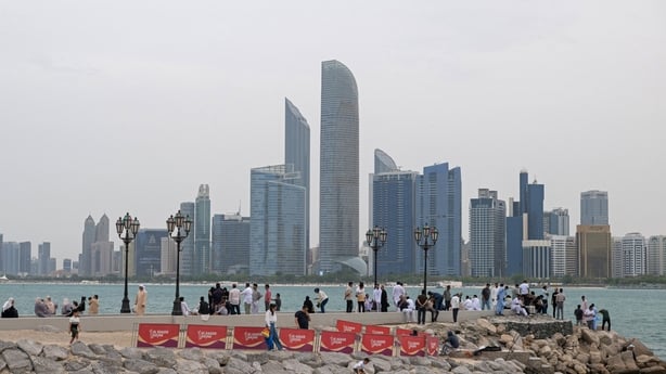 People are seen in the foreground with the skyscrapers of abu dhabi in the distance