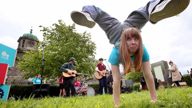 A girl performs an acrobatic trick with musicians in the background at the Cruinniú na nÓg 2026 launch at TUD Grangegorman