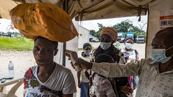 A border health officer at the Busunga crossing between Uganda and the Democratic Republic of Congo checks a traveller’s temperature