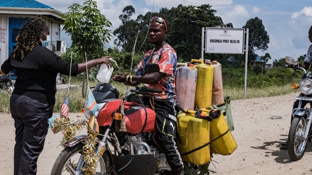 A port health officer sanitises the hands of a motorbike rider transporting goods across the border between Uganda and the Democratic Republic of Congo