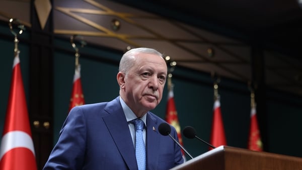 Turkish President Recep Tayyip Erdogan speaking at a podium with a microphone and Turkey flags in the background