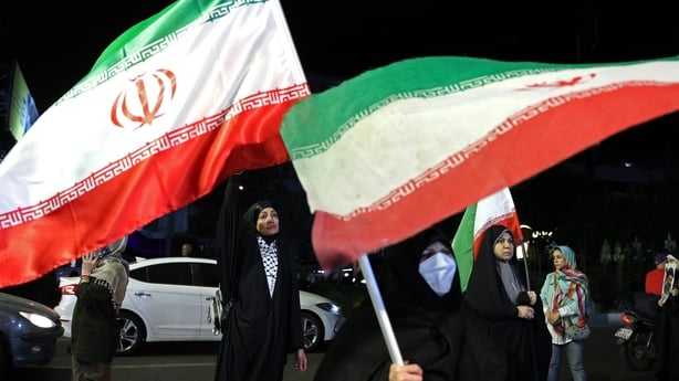 Women hold Iran's national flags during an anti-US and Israel protest at the Hafte Tir Square in Tehran on May 17, 2026. President Donald Trump issued a fresh warning to Iran on May 17, saying it had to move quickly towards a peace deal or "there won't be anything left of them." Washington, locked i