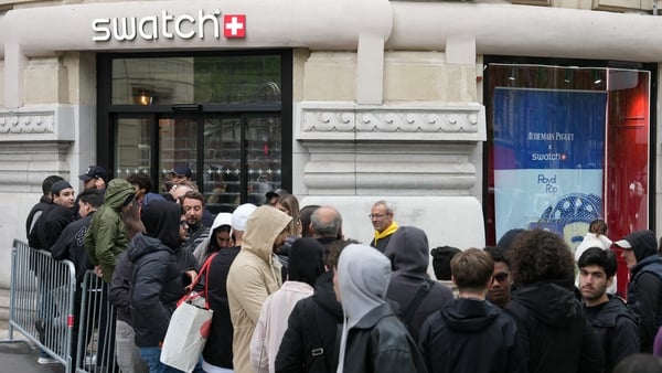 Shoppers queue in front of a closed shop of Swiss watch company Swatch