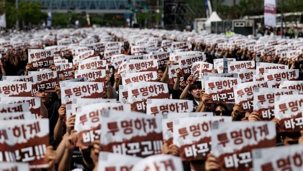 Image of workers holding up red and white banners with South Korean writing on them