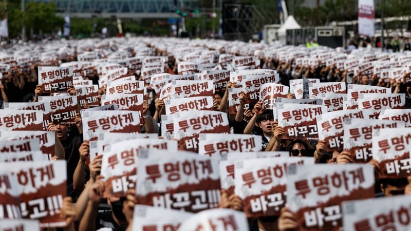 Image of workers holding up red and white banners with South Korean writing on them