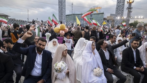 Couples sit together as a groom shouts slogans during a mass wedding ceremony for Self-Sacrificing Couples, organized by the Islamic Revolutionary Guard Corps (IRGC) in southern Tehran, Iran, on May 18, 2026. The term 'Self-sacrificing,' known as Jan-fada