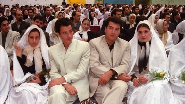 Couples sitting together ahead of a mass weddings ceremony in Tehran