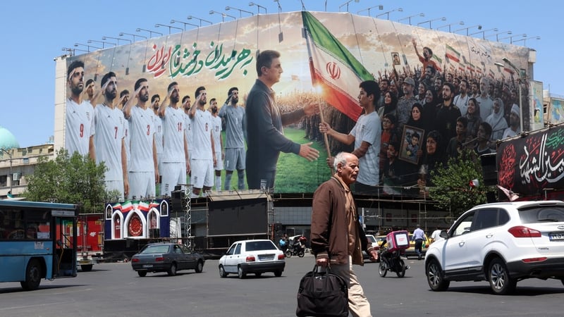 An Iranian man walks past a huge billboard supporting Iran’s national football team
