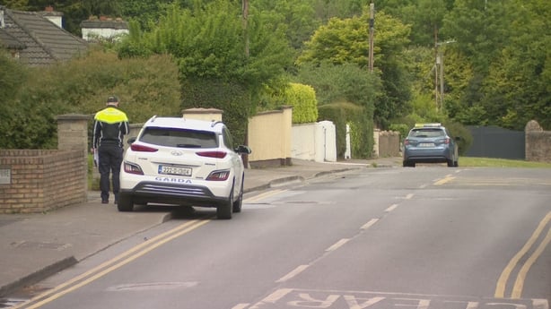 a garda stands beside a garda car on a road in blanchardstown