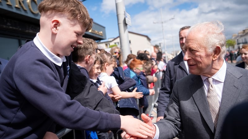 king charles shakes hands with a young boy