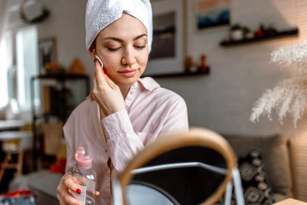 Young woman with problematic skin doing her face care routine.
