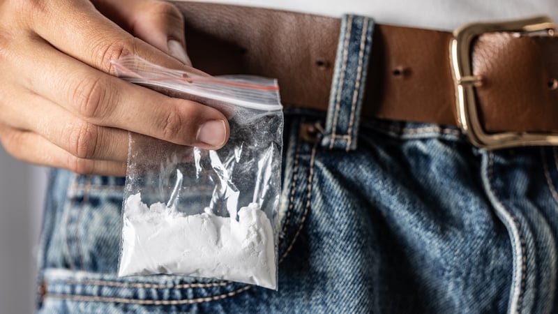 The hand selects a package with a drug - cocaine in the back pocket of jeans