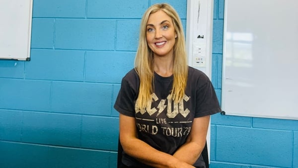 Study Hub 2026 guest Aisling Kearns Geography teacher sits posing in front a blue wall and white board in a classroom