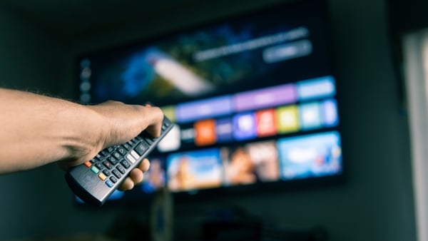 Hand holding a remote control, browsing streaming services on a smart tv