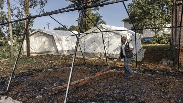 A man walks through the burned remains of a destroyed Médecins Sans Frontières (MSF) emergency tent in Mongbwalu, DRC