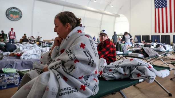 Natalie Bouriche, of Anaheim, sits on a cot where she spent the night, along with her son, Abde Atti, 16, seated behind her having evacuated to Freedom Hall, due to the chemical leak, on Saturday, May 23, 2026, in Fountain Valley, CA. Tens of thousands told to evacuate after a 34,000-gallon tank of 