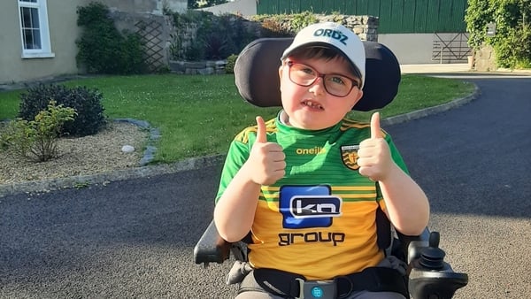 Picture of a young boy in a wheelchair giving a thumbs up