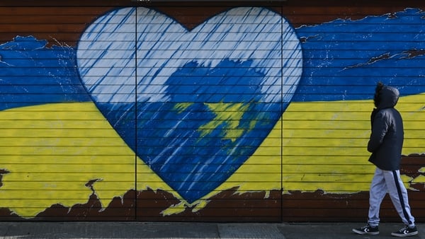 A young boy walks past a mural related to the war in Ukraine in Dublin