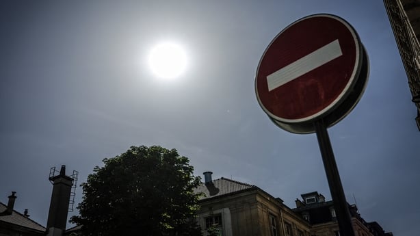 the sun shining above a no-entry road sign with no clouds in the sky
