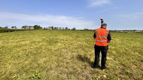 A man in an orange hi-vis vest uses search equipment in a field
