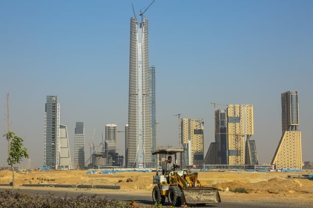 Skyscraper buildings in a desert with a construction vehicle in the foreground