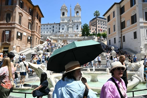 Tourists shield themselves from the sun with hats and umbrellas at the Spanish steps in Rome