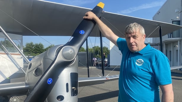 a photograph of oliver murphy with one hand on the propellor of a vintage plane